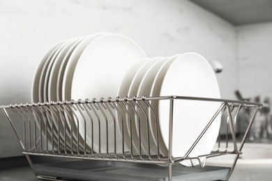 Photo of Drying rack with clean dishes on kitchen counter