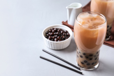 Photo of Bubble milk tea with tapioca balls on light table. Space for text