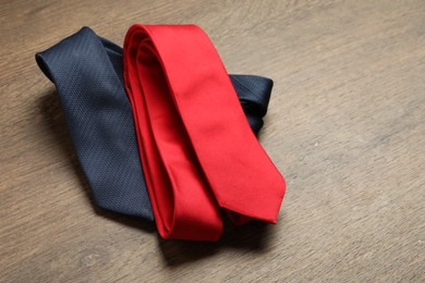 Photo of Red and blue neckties on wooden table, above view. Space for text