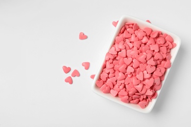 Photo of Pink heart shaped sprinkles and bowl on white background, top view