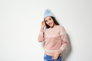 Young woman in warm sweater and knitted hat on white background. Celebrating Christmas