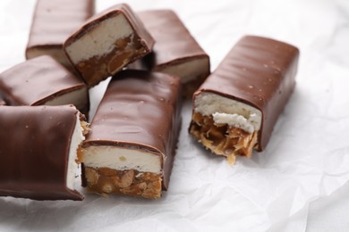 Tasty chocolate bars with nougat and nuts on white table, closeup