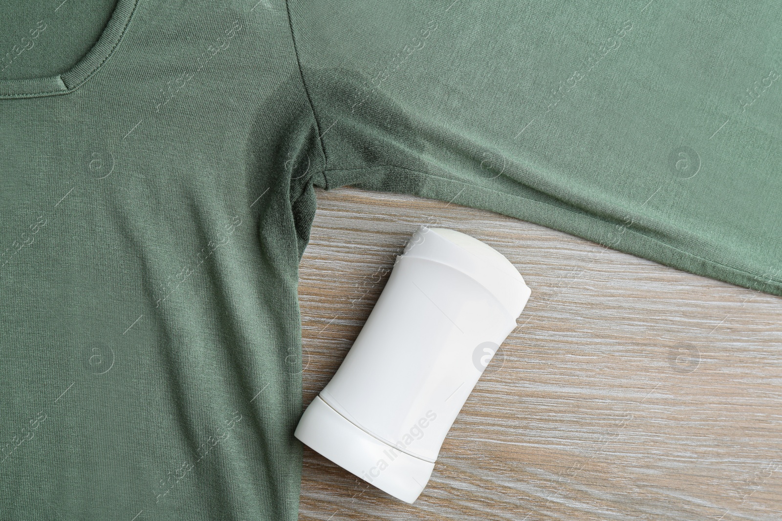 Photo of Clothes with stain and deodorant on wooden background, top view