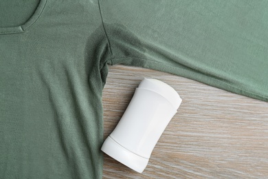 Clothes with stain and deodorant on wooden background, top view