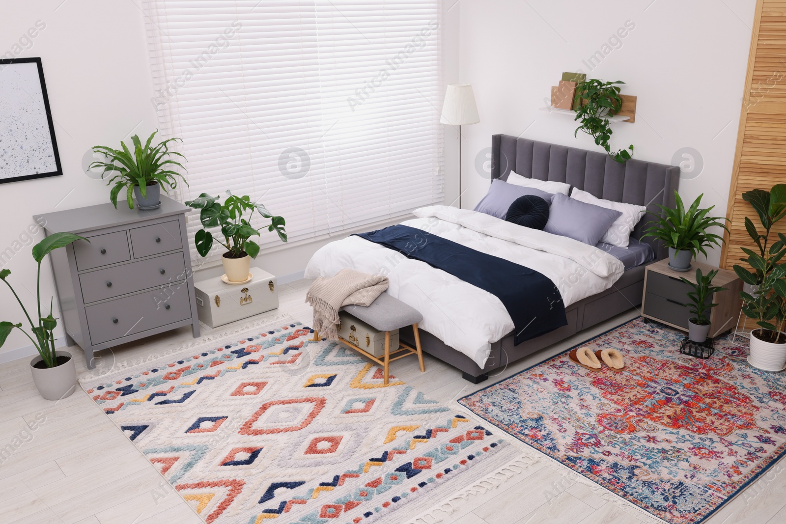 Photo of Stylish bedroom with double bed and beautiful green houseplants, above view. Modern interior