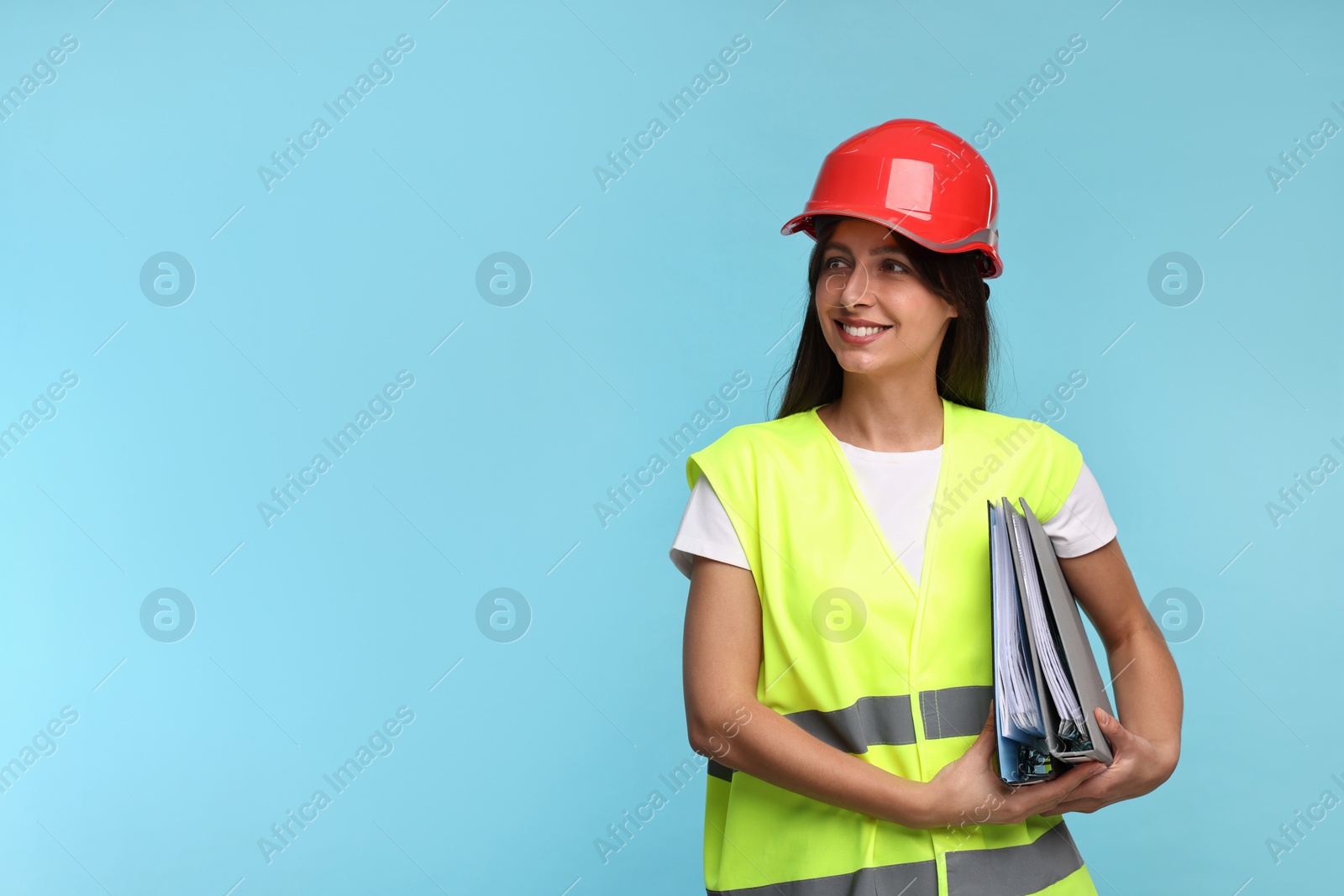 Photo of Architect in hard hat with folders on light blue background, space for text