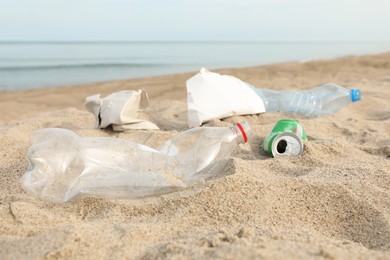 Garbage scattered on beach near sea, closeup. Recycling problem
