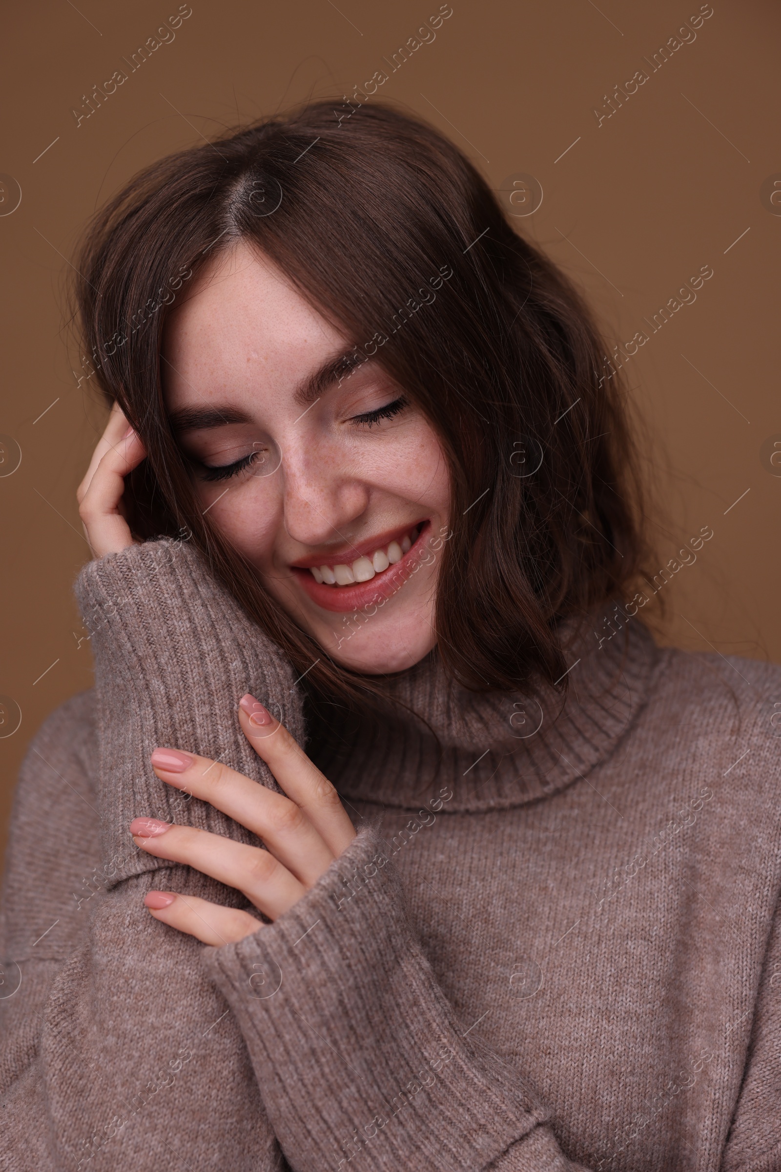 Photo of Portrait of beautiful young woman in warm sweater on brown background