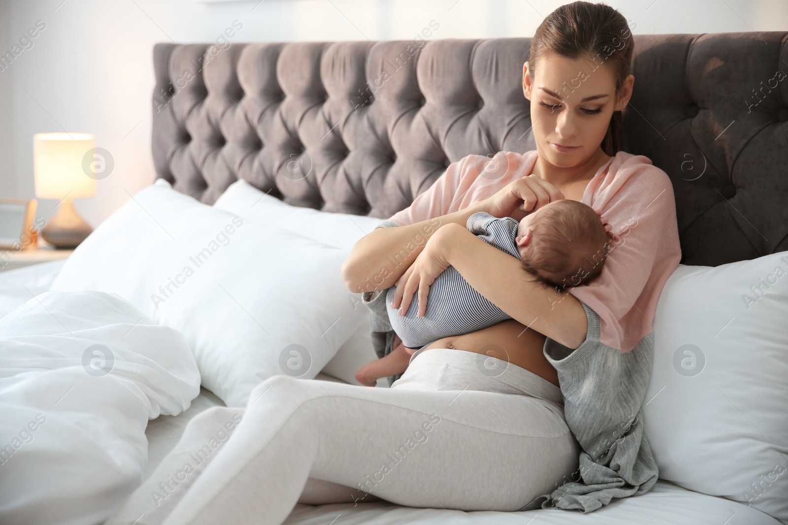 Photo of Young woman breastfeeding her baby in bedroom