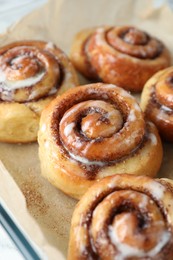 Photo of Baking dish with tasty cinnamon rolls on white table, closeup