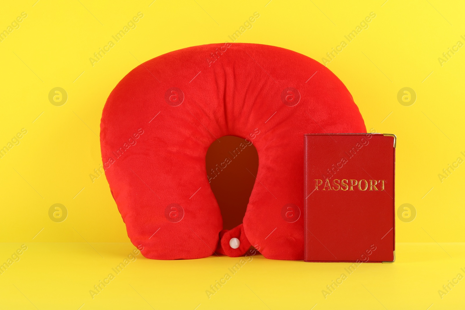 Photo of Red travel pillow and passport on yellow background