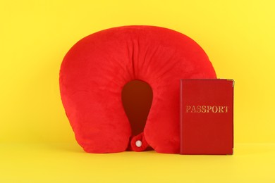 Photo of Red travel pillow and passport on yellow background