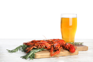 Delicious red boiled crayfishes and beer on wooden table against white background