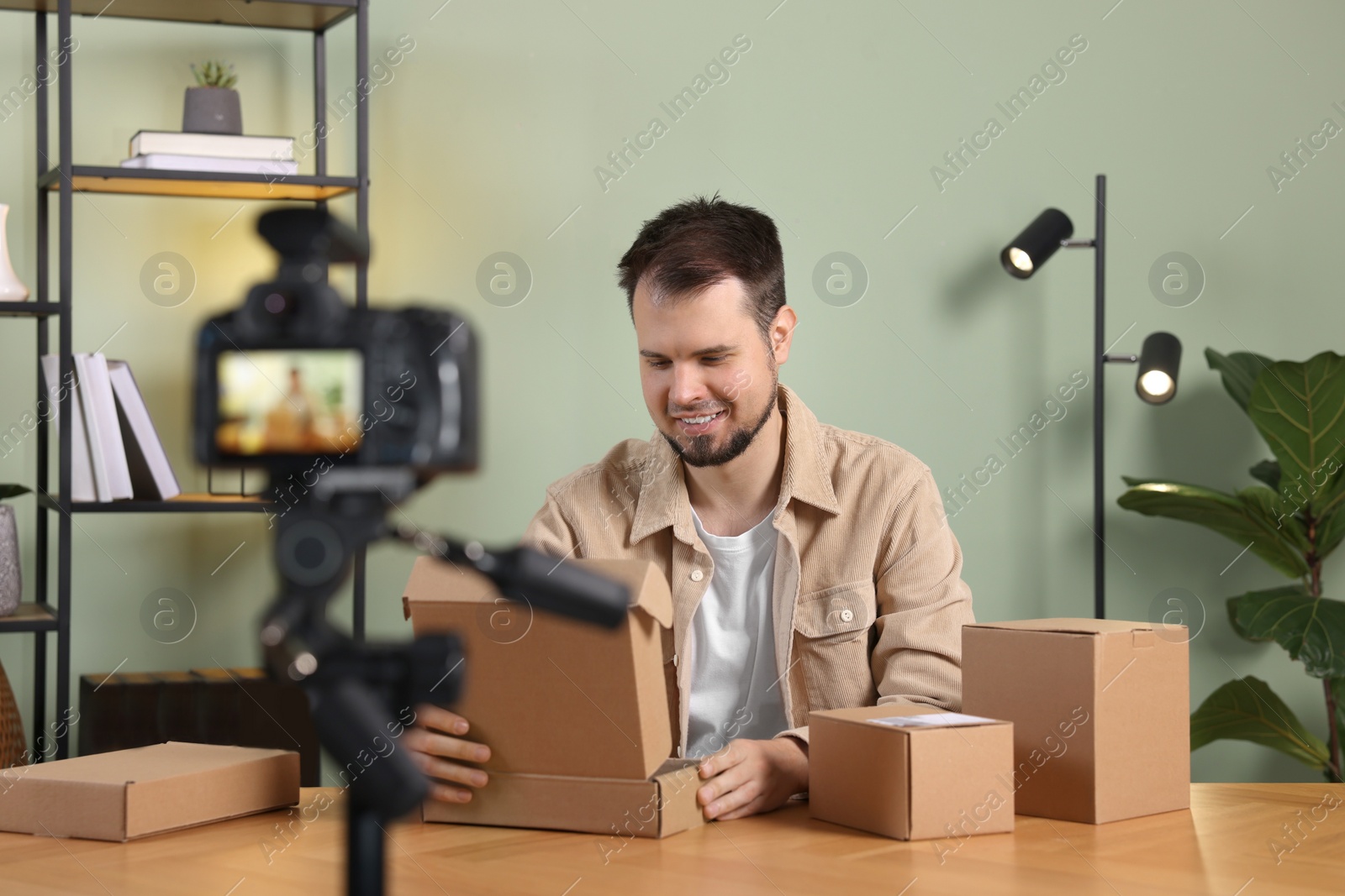 Photo of Smiling blogger with many parcels recording video at home