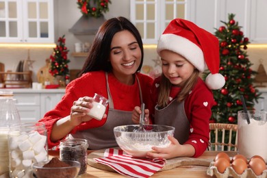 Photo of Happy mother and her daughter making dough for Christmas cookies at home