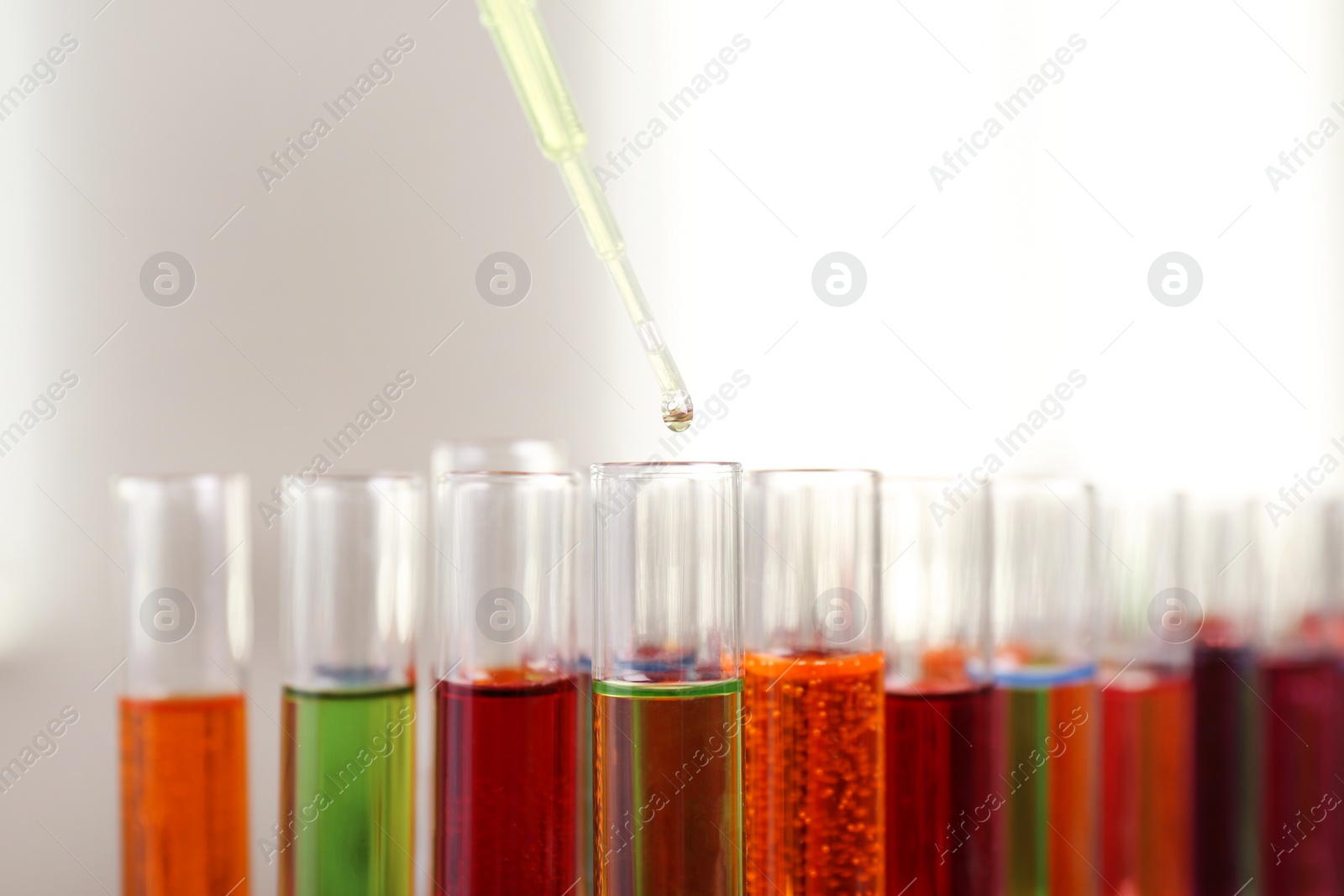 Photo of Dripping color liquid into test tube, closeup. Solution chemistry