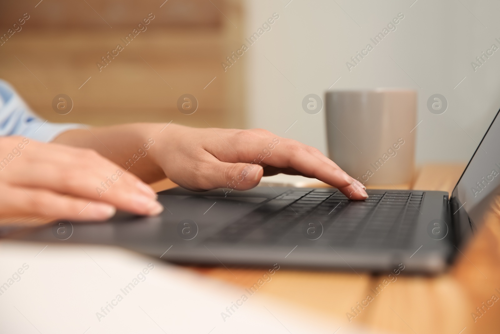 Photo of Woman working with modern laptop at wooden table, closeup