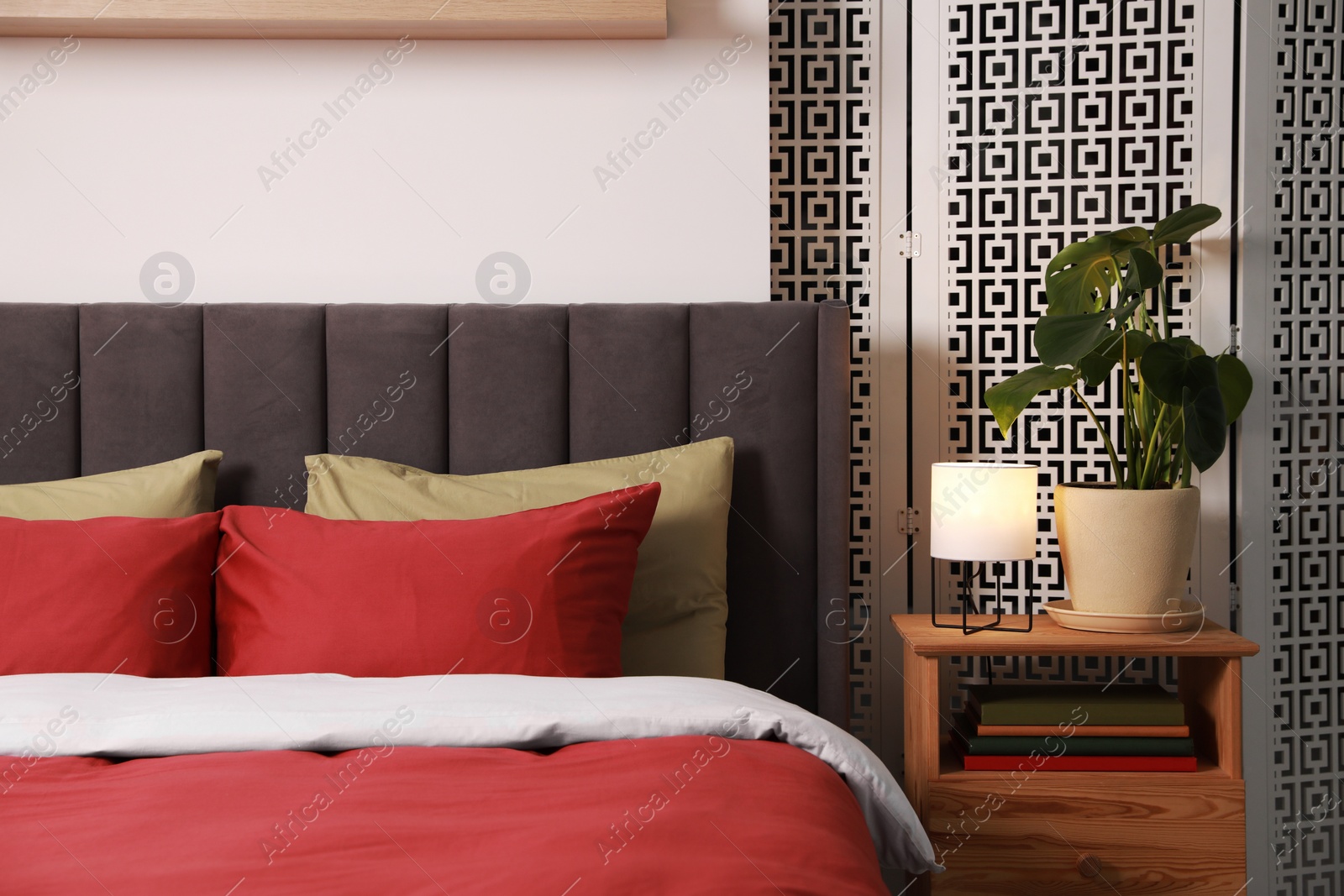 Photo of Stylish bedroom interior with comfortable bed, nightstand and green houseplant