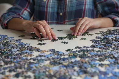 Young woman playing with puzzles at table, closeup