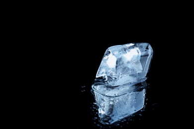 Photo of Ice cube on black mirror surface. Space for text
