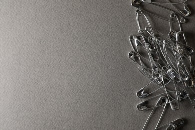 Photo of Many safety pins on light grey textured background, flat lay. Space for text