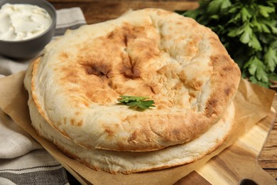 Photo of Loaves of delicious homemade pita bread on wooden table, closeup