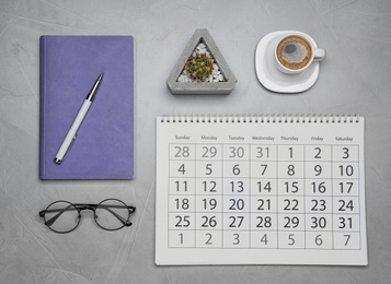 Photo of Flat lay composition with calendar and cup of coffee on grey table