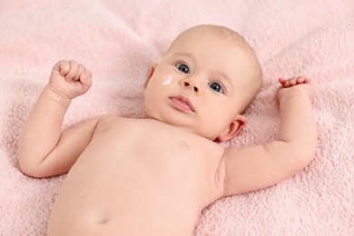 Photo of Cute little baby with cream on face on pink blanket, above view