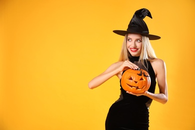 Photo of Beautiful woman in witch costume with jack o'lantern on yellow background, space for text. Halloween party