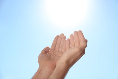 Photo of Man reaching hands to blue sky outdoors on sunny day, closeup