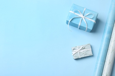 Photo of Beautiful gift boxes and wrapping paper rolls for decor on color background. Space for text