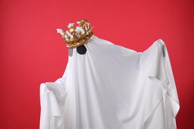 Photo of Person in ghost costume and luxurious crown on red background