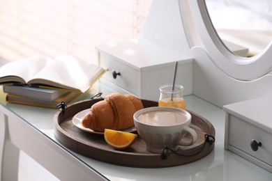 Photo of Wooden tray with delicious breakfast on dressing table indoors
