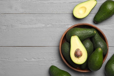 Photo of Delicious ripe avocados on grey wooden table, flat lay. Space for text