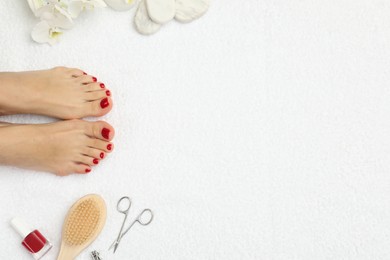 Photo of Woman with stylish red toenails after pedicure procedure and orchid flowers on white terry towel, top view. Space for text