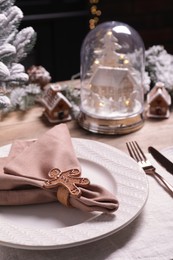 Photo of Plate with fabric napkin, cutlery and festive decor on wooden table