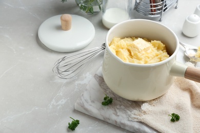 Photo of Saucepan with tasty mashed potato on gray table