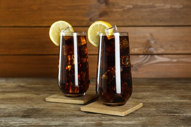 Photo of Glasses of refreshing soda water with ice cubes and lemon slices on wooden table