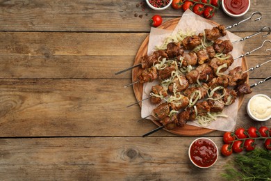 Photo of Metal skewers with delicious meat and vegetables served on wooden table, flat lay. Space for text