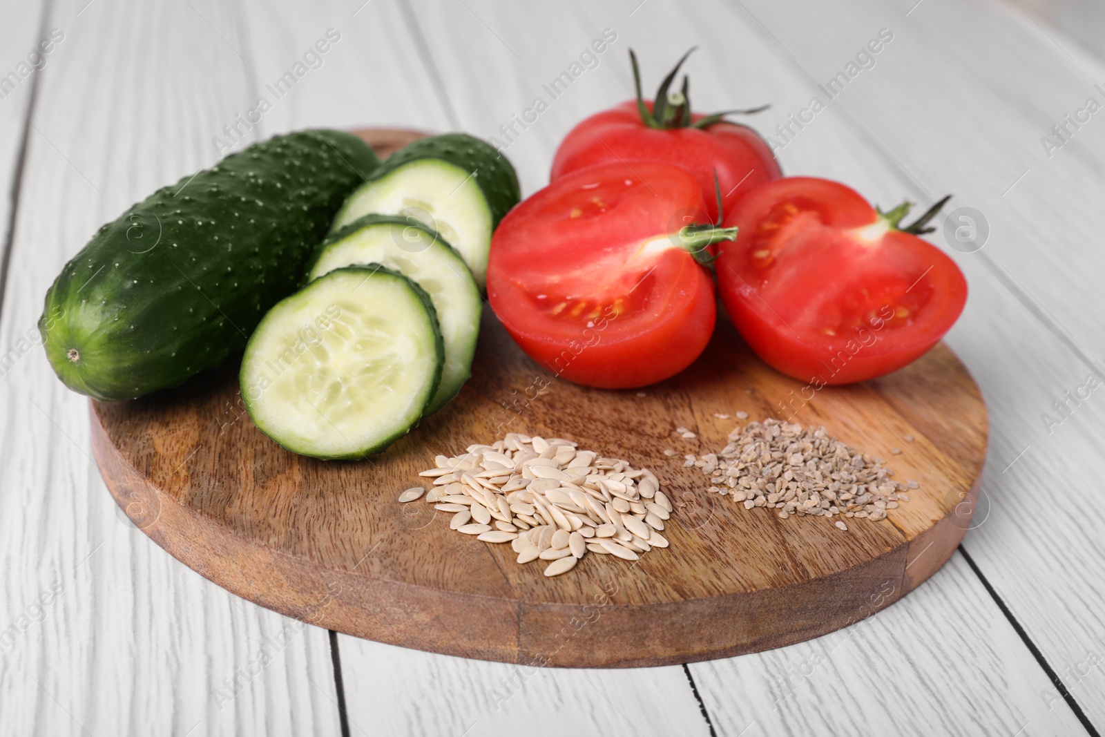 Fresh cucumbers, tomatoes and vegetable seeds on white wooden table, closeup Photo of Fresh cucumbers, tomatoes and vegetable seeds on white wooden table, closeup
