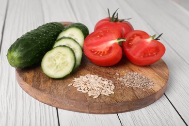 Photo of Fresh cucumbers, tomatoes and vegetable seeds on white wooden table, closeup