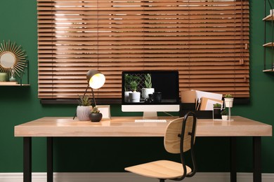 Photo of Comfortable workplace with modern computer near window in room. Interior design