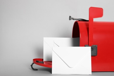 Photo of Open red letter box with envelopes on light background, closeup. Space for text