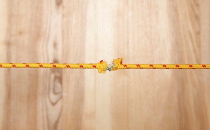 Photo of Frayed rope at breaking point on wooden background