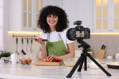 Photo of Smiling food blogger explaining something while recording video in kitchen
