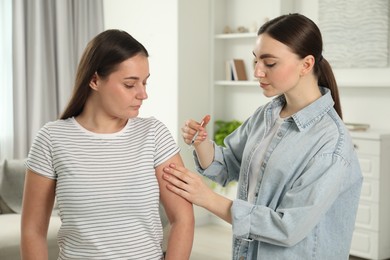 Photo of Woman giving insulin injection to her diabetic friend at home