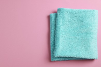 Photo of Soft folded light blue towel on violet background, top view. Space for text