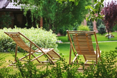 Photo of Wooden deck chairs in beautiful garden on sunny day