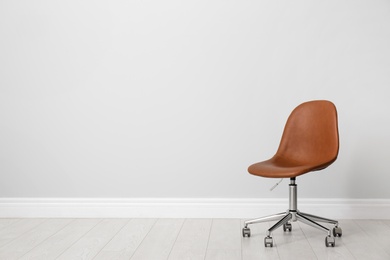 Photo of Comfortable office chair near light wall indoors. Space for text