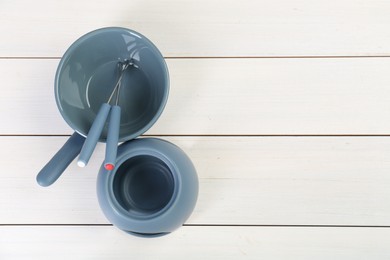 Photo of Fondue set on white wooden table, flat lay. Space for text